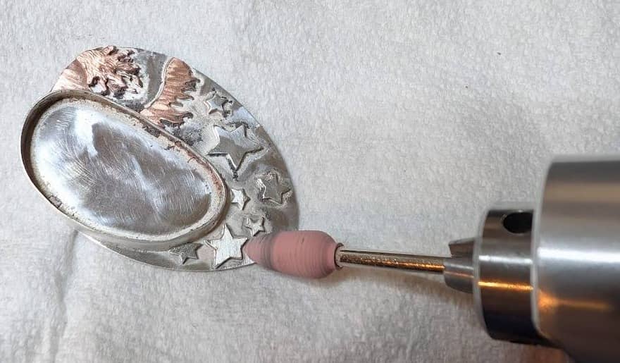 Silicon point attachment being used to clean around decoration on a pendant