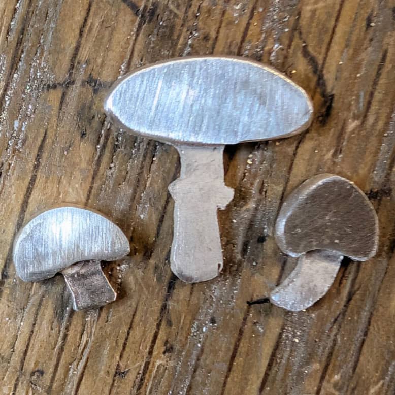 Three cut out silver mushrooms
