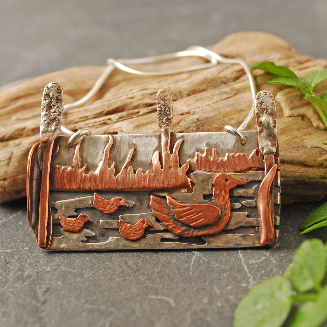 silver pendant with copper duck family and water plants