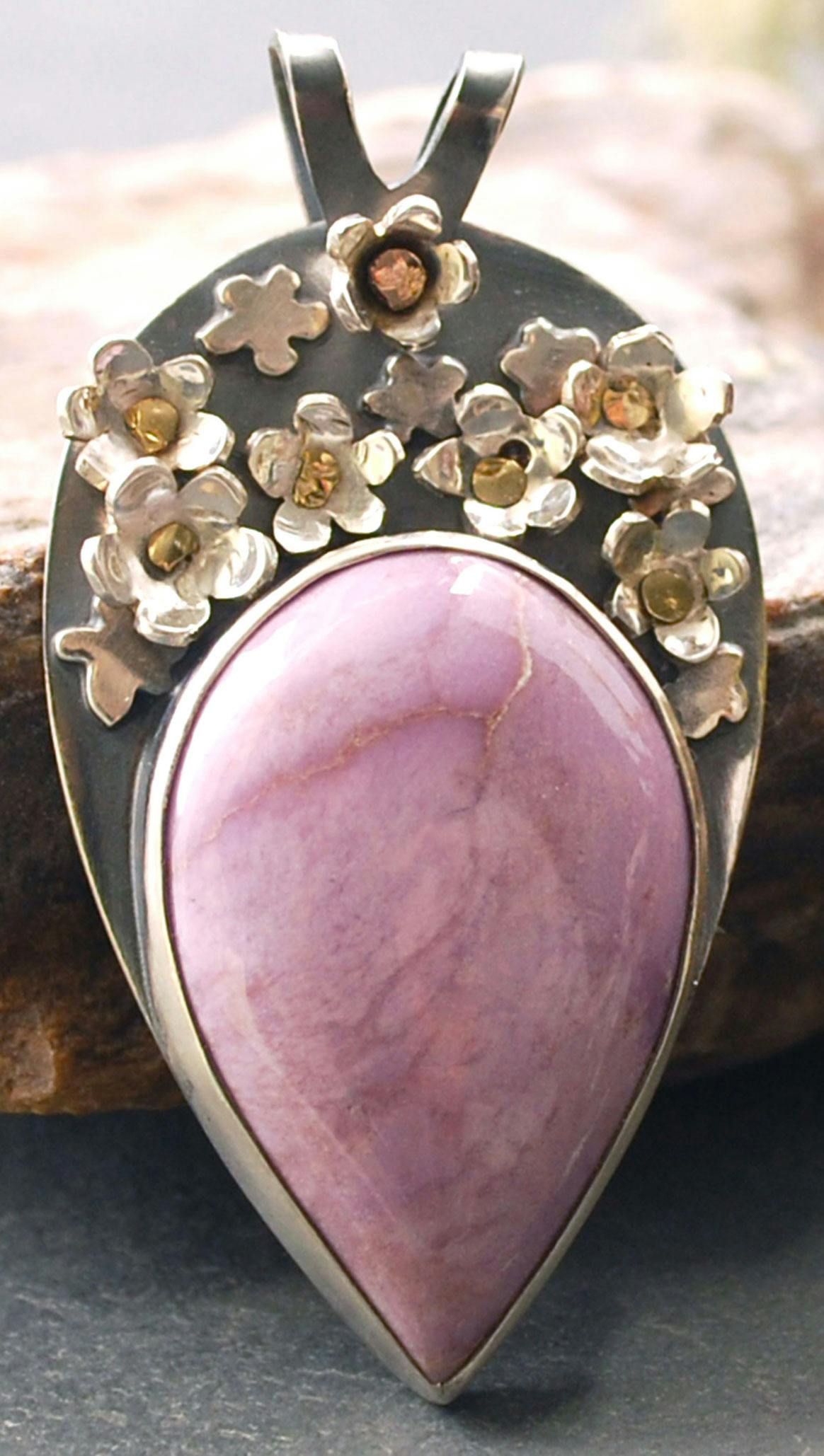 Silver pendant with pink phosphiderite stone, many three dimensional silver flowers above the stone