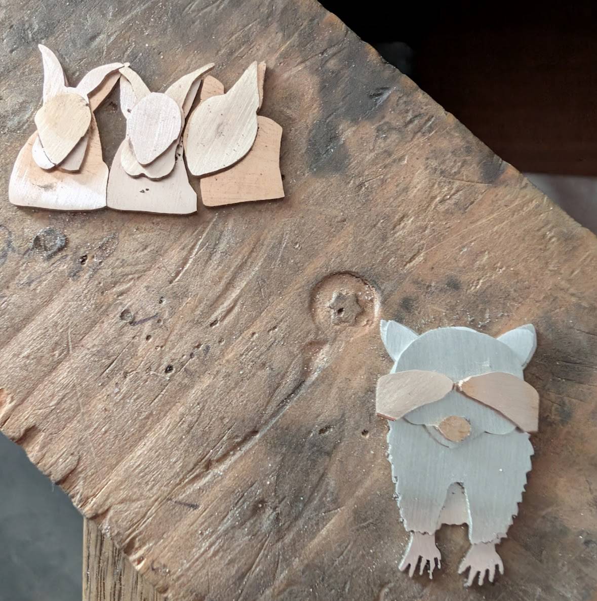 pieces of metal sawn out in the shapes of three rabbits and one racoon