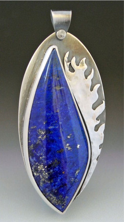 Silver pendant with blue flame shaped lapis lazuli cabochon, hammered silver flames next to stone