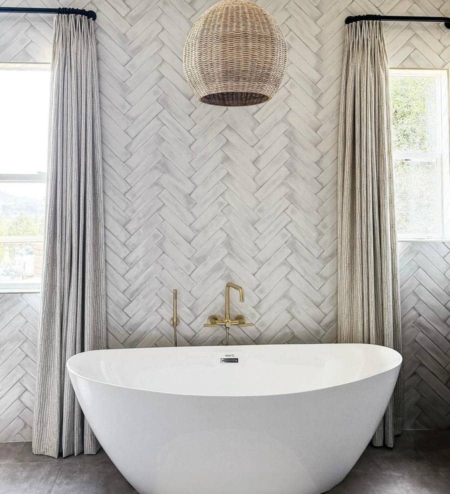 A serene bathroom with a freestanding tub, brass fixtures and white herringbone tile