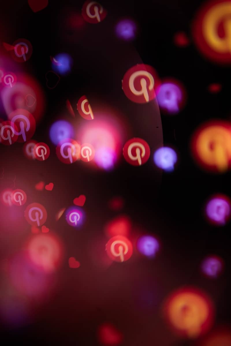 Pinterest logos and hearts float in a dark, bokeh background.