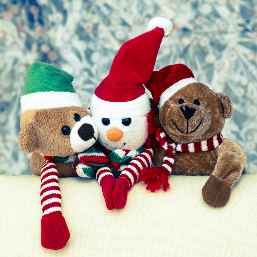 three stuffed animals with holiday hats and scarfs