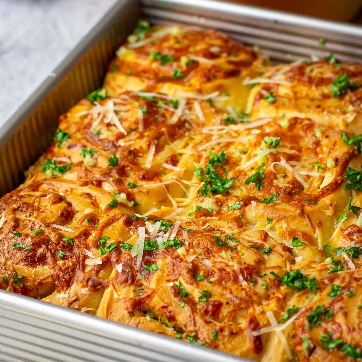 Cheesy sourdough garlic rolls in a baking pan