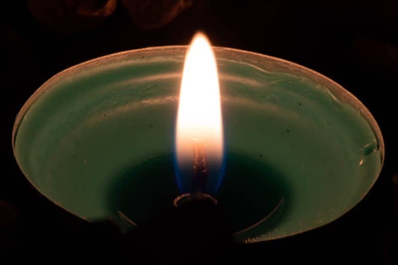 A lit green candle with a bright flame
