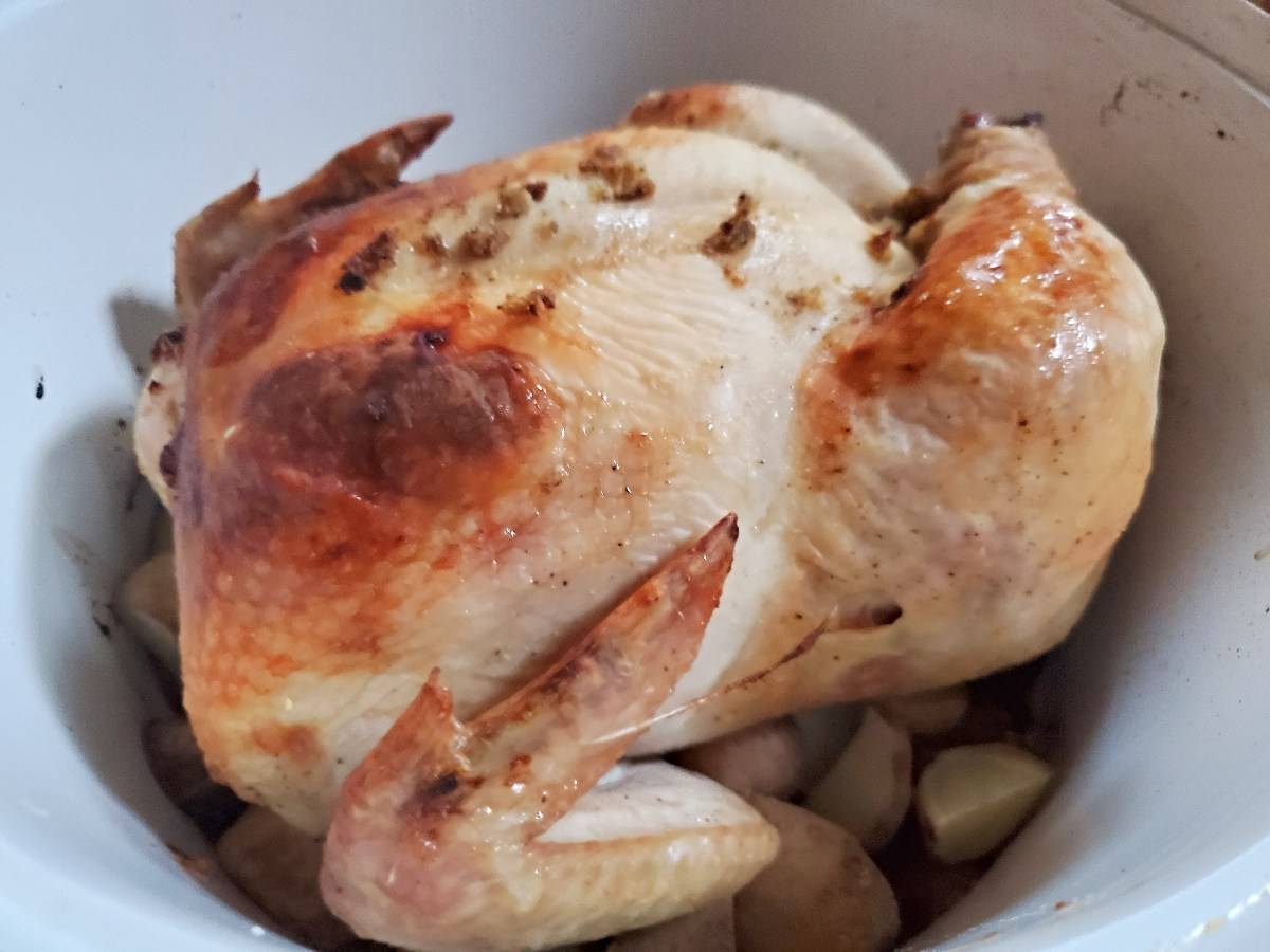 Closeup of a roasted chicken in a white pan.