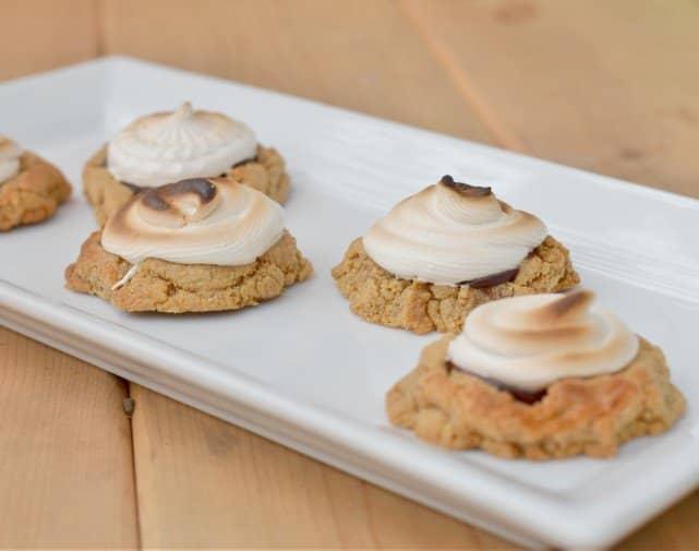 S'mores cookies with toasted marshmallow tops sit on a white tray.
