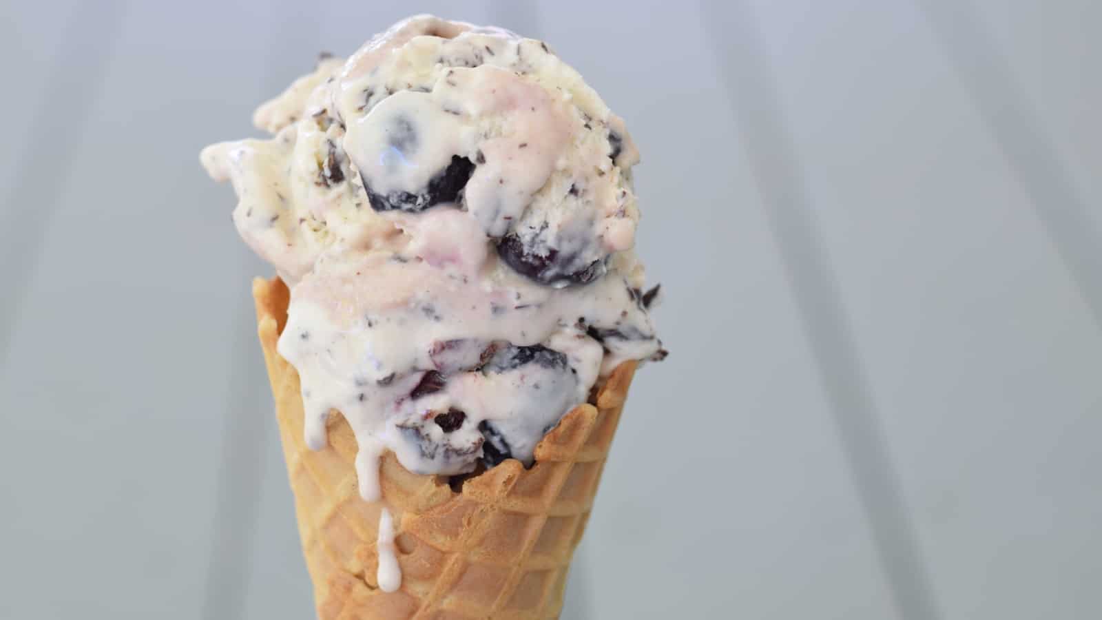 Cherry chip ice cream in a waffle cone dripping down.