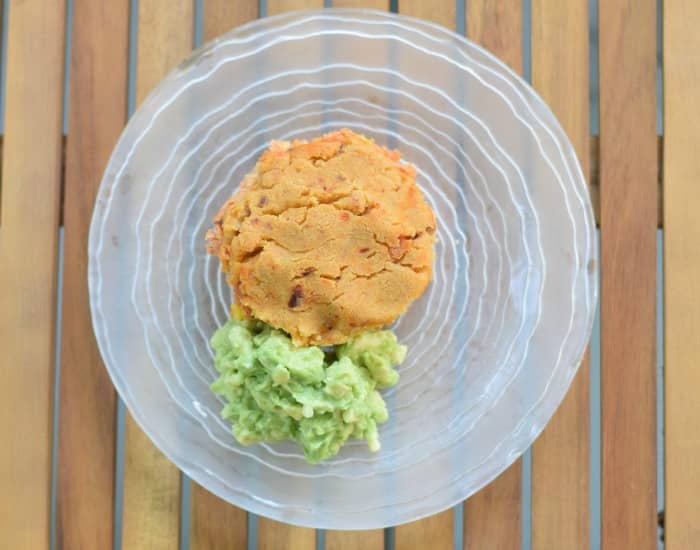 Overhead of a tamale pot pie on a clear glass plate with guac next to it.