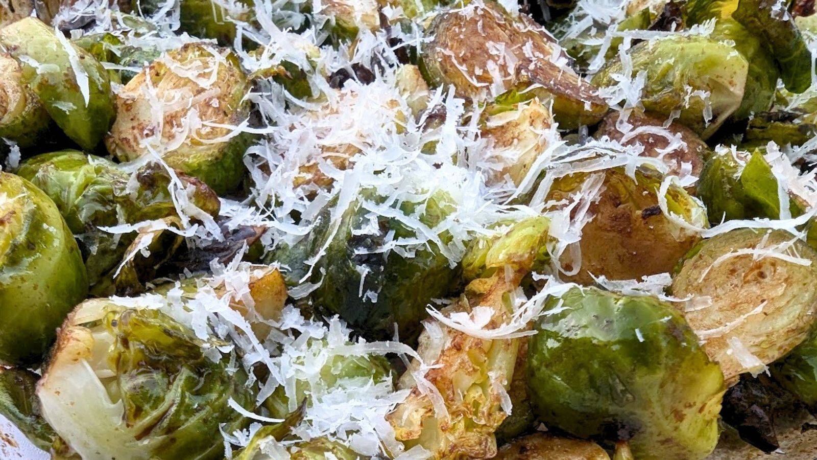 Closeup of Brussels sprouts topped with parmesan cheese.