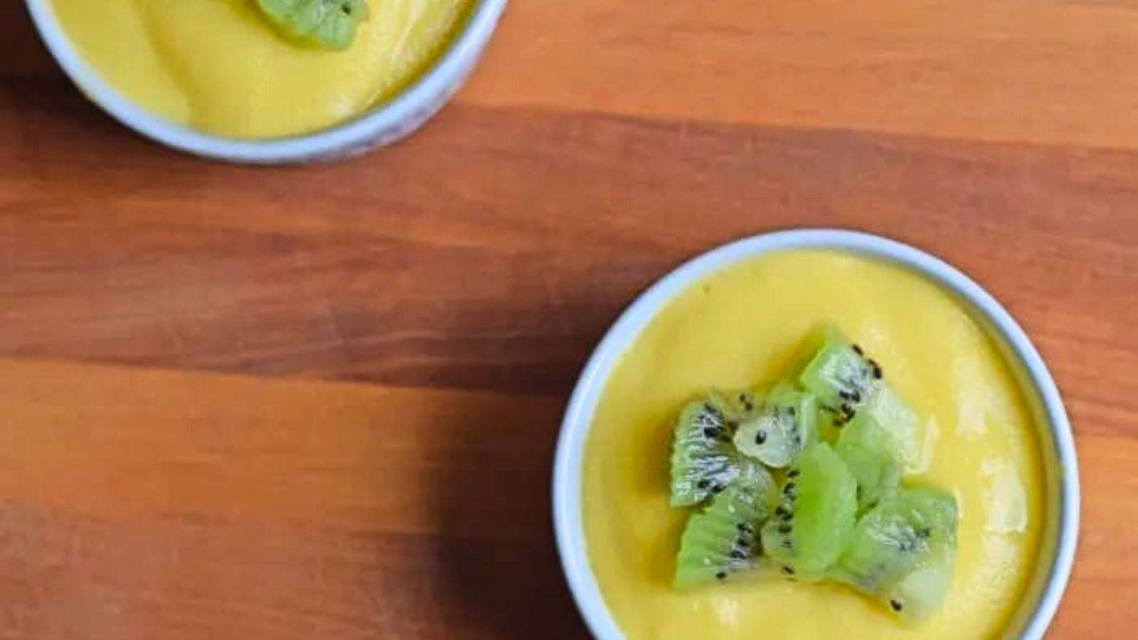 Overhead of a ramekin holding mango custard with chopped kiwi on top.