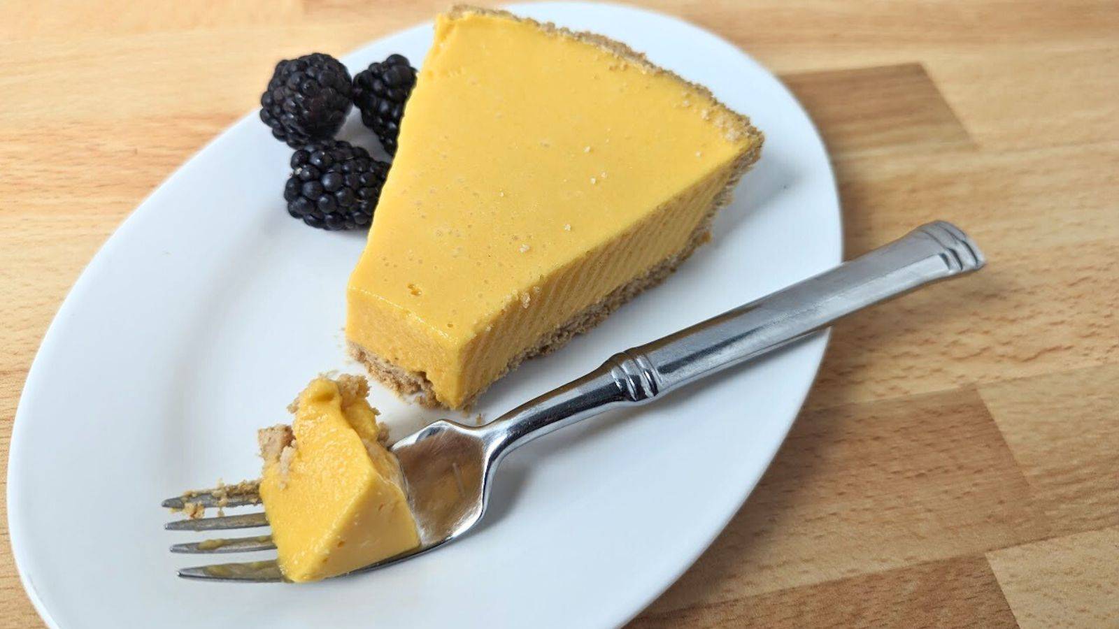 Mango pie on a plate with a fork that has cut out a bite.