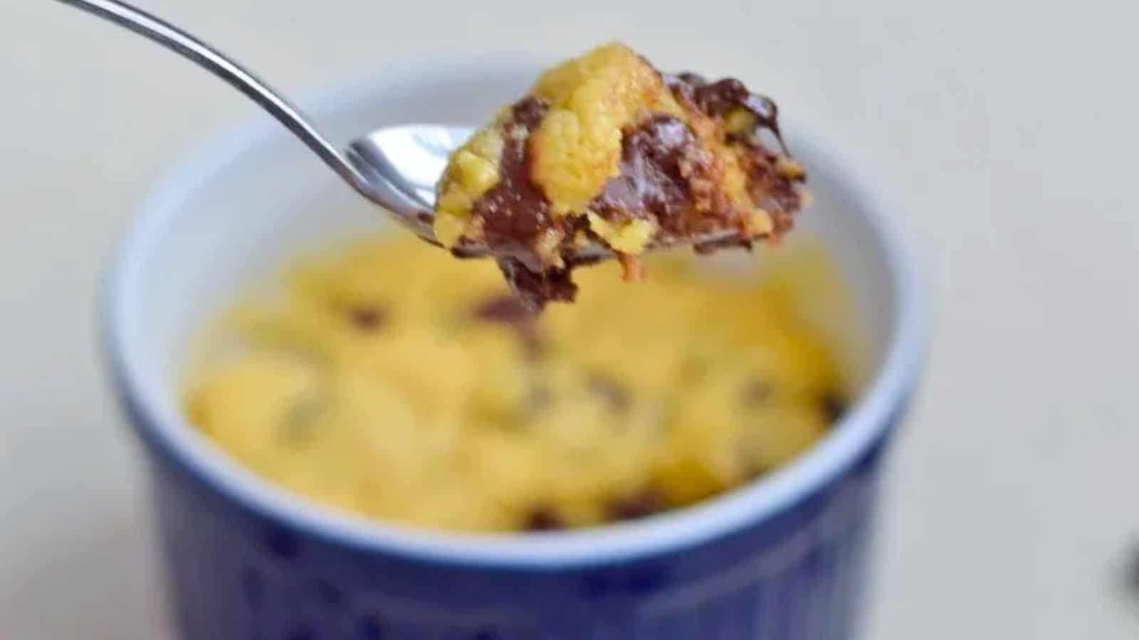 Image shows a spoon holding a bite of a chocolate chip mug cake.