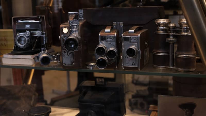 A bunch of old cameras sitting on a glass table