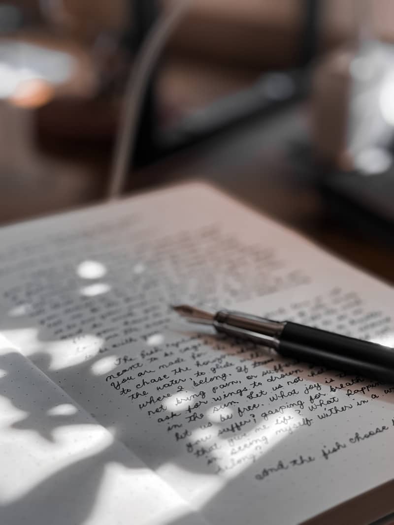 A fountain pen rests on a handwritten page.