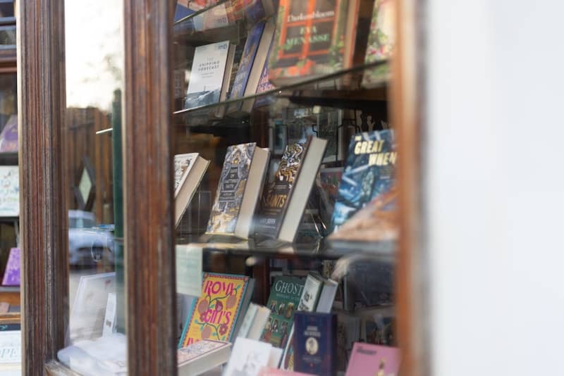 A bookshelf filled with lots of books behind a glass door