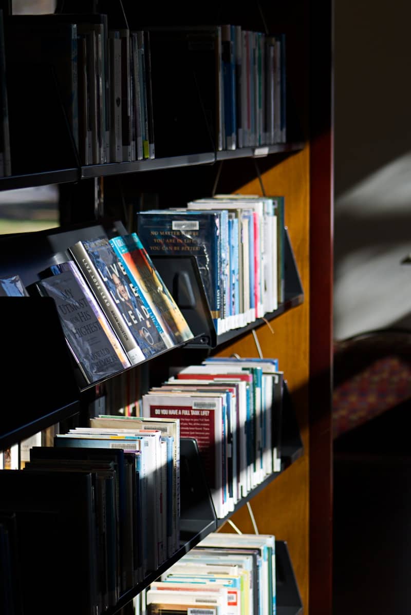 A bookshelf filled with lots of books next to a window