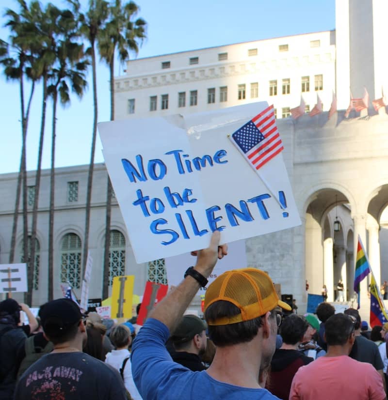 Protester holds sign: "no time to be silent!"