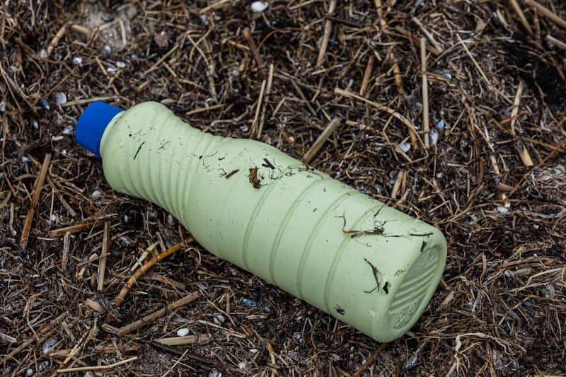 a green plastic bottle laying on the ground