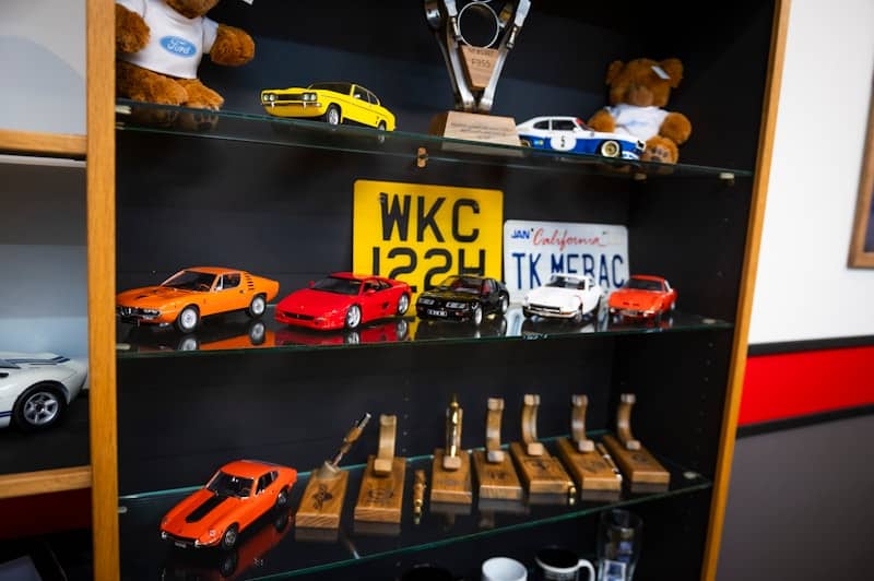A shelf displays car models, trophies, and other items.