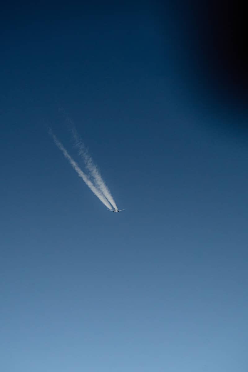 Airplane leaving a contrail across a clear blue sky.