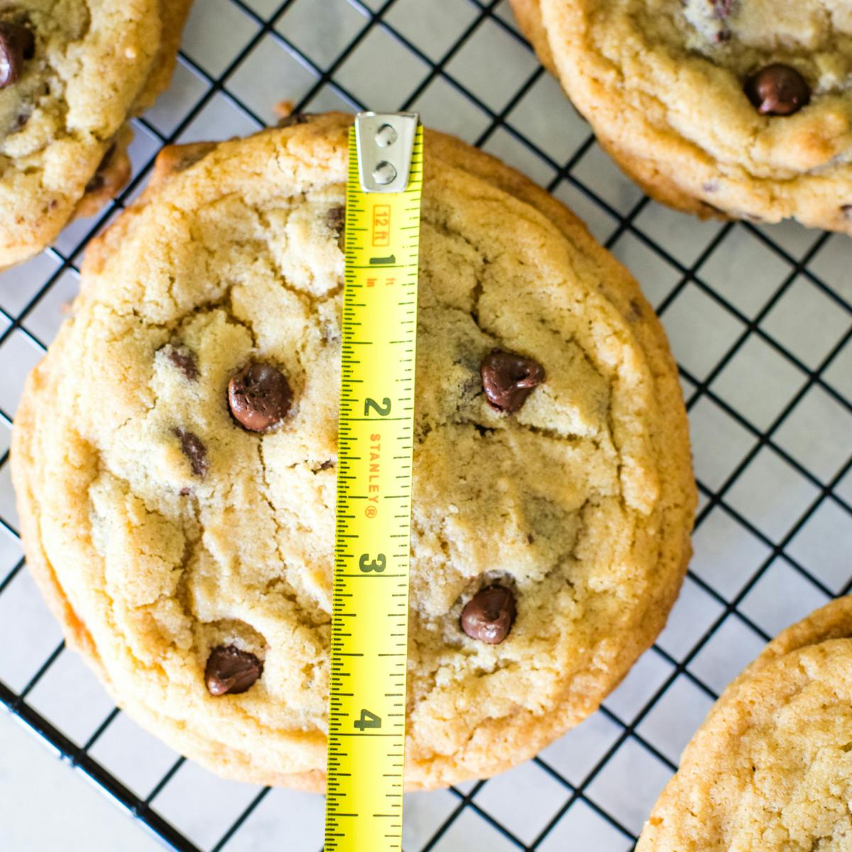 chocolate chip cookie on cooling rack with measuring tape