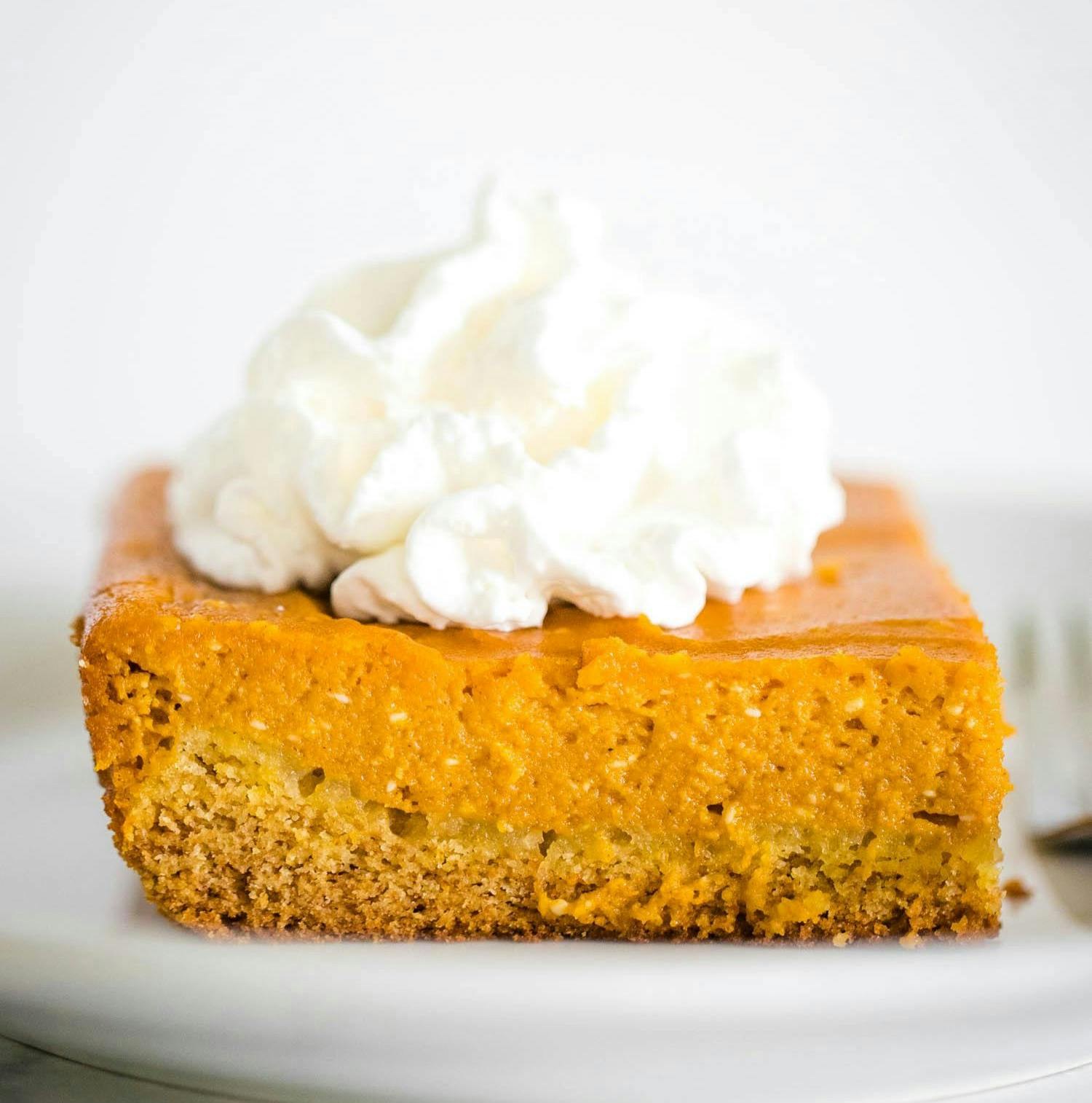 pumpkin gooey cake on plate topped with whipped cream