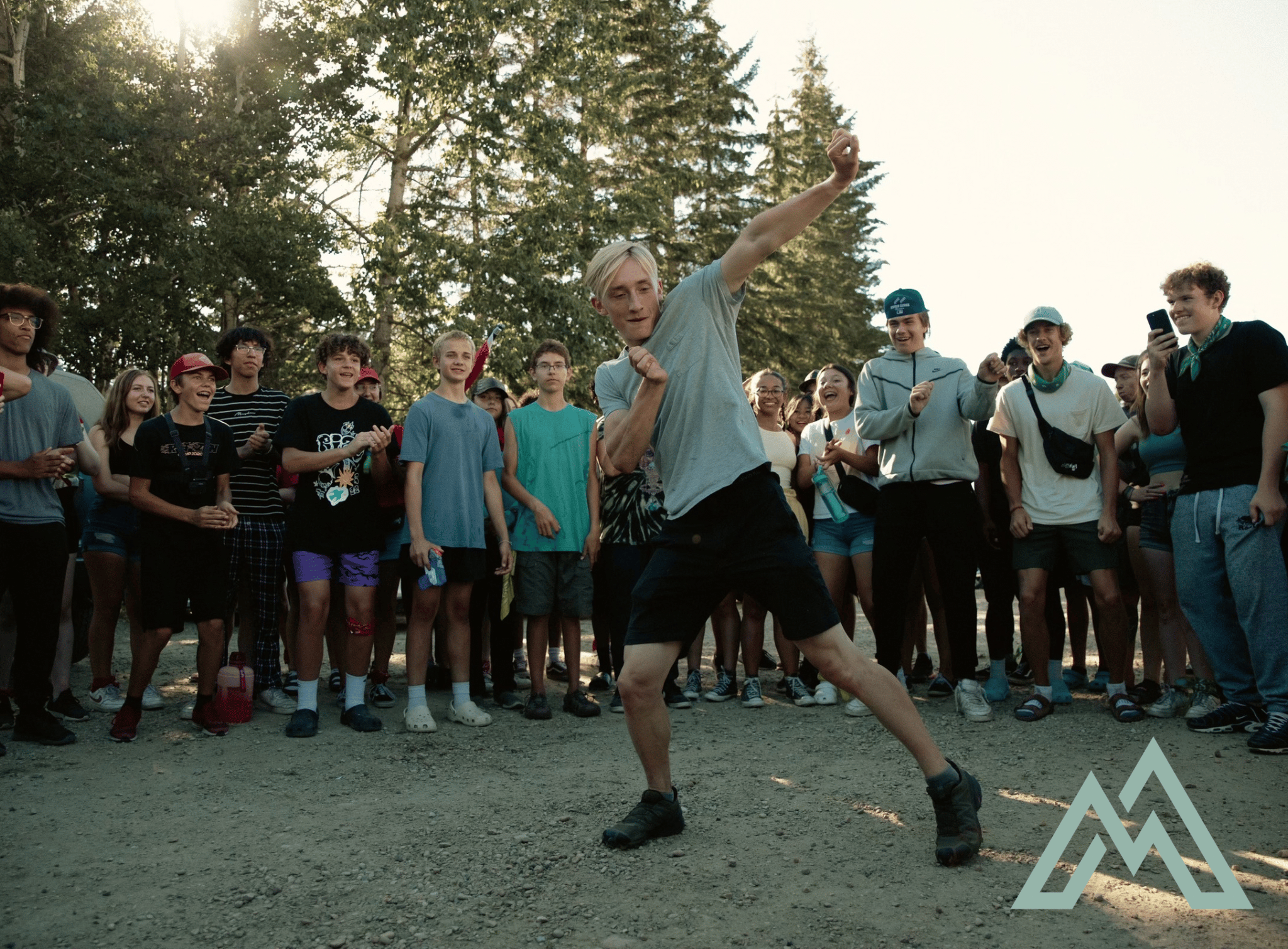 A group of young people excitedly watching a dancer performing in front of them.