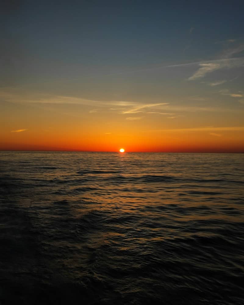 The low sun on the horizon above a dark rippling ocean