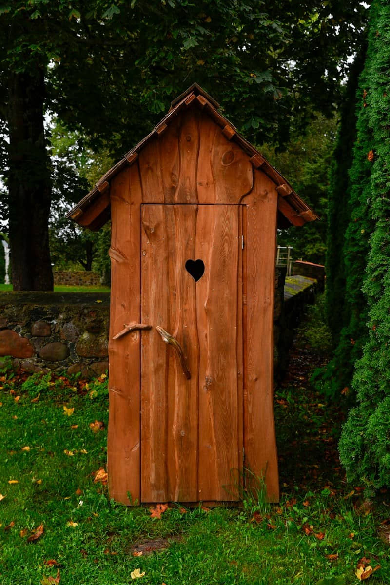 Rustic wooden outhouse with heart-shaped window