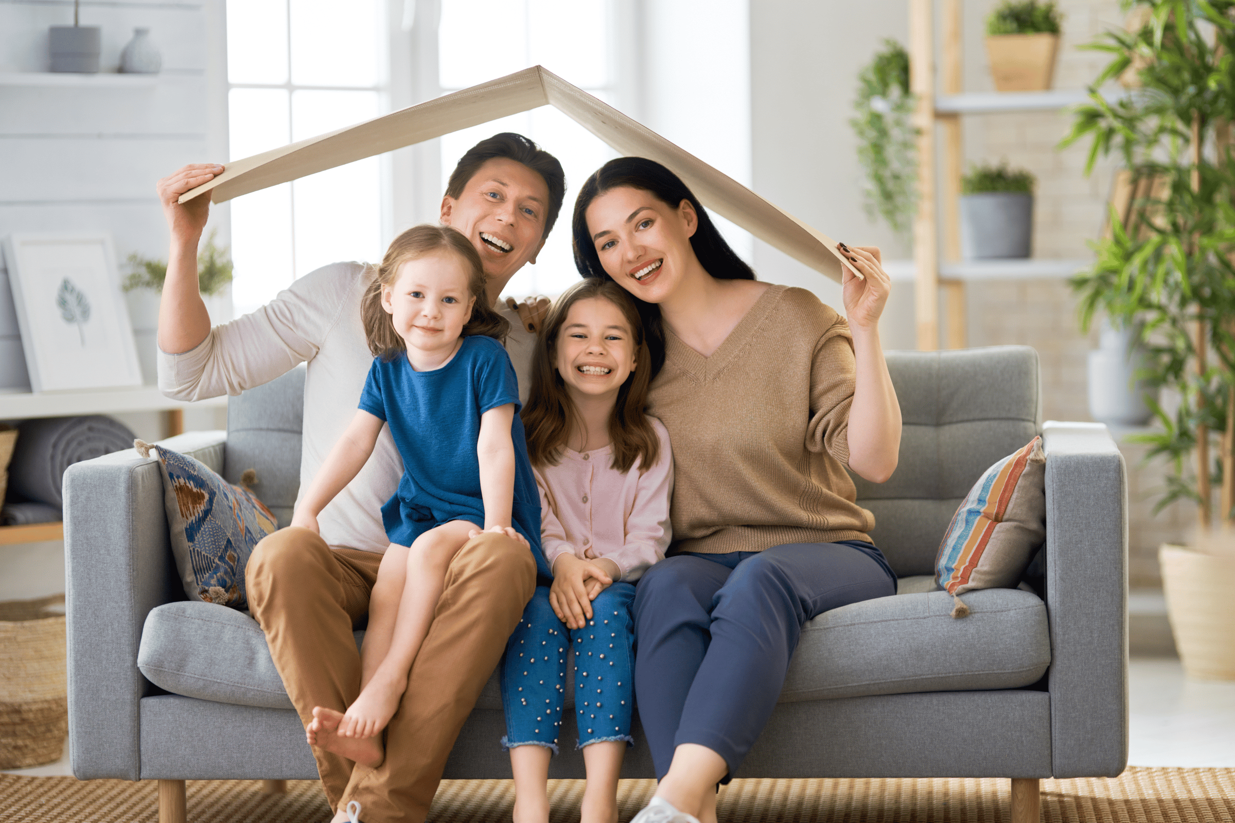 The image shows a happy family sitting on a couch and smiling.  This image conveys How to Encourage Long-Term Tenancy