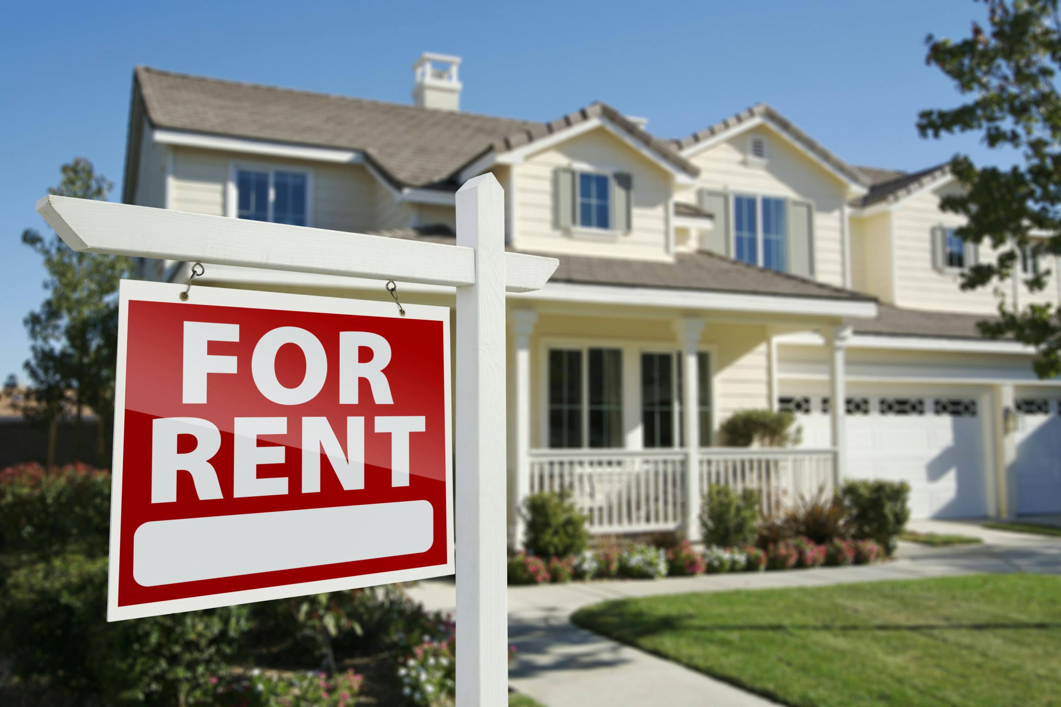 The image shows a two-story house with a peaked roof and a front porch. On the front lawn is a red and white For Rent sign. This image conveys The Rental Market for Single-Family Homes Is Set to Soar.