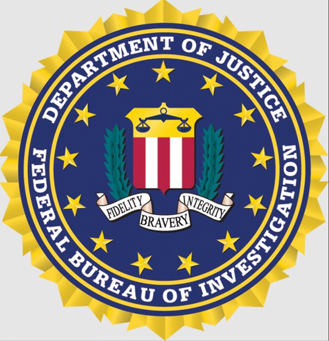 The image is of the seal of the FBI. The blue and gold seal has the words Department of Justice encircling the top, with the words Federal Bureau of Investigation encircling the bottom. In the center are the words, Fidelity Bravery Integrity.  The image conveys the topic FBI Searches Property Management Company in Rent Price-Fixing Investigation.