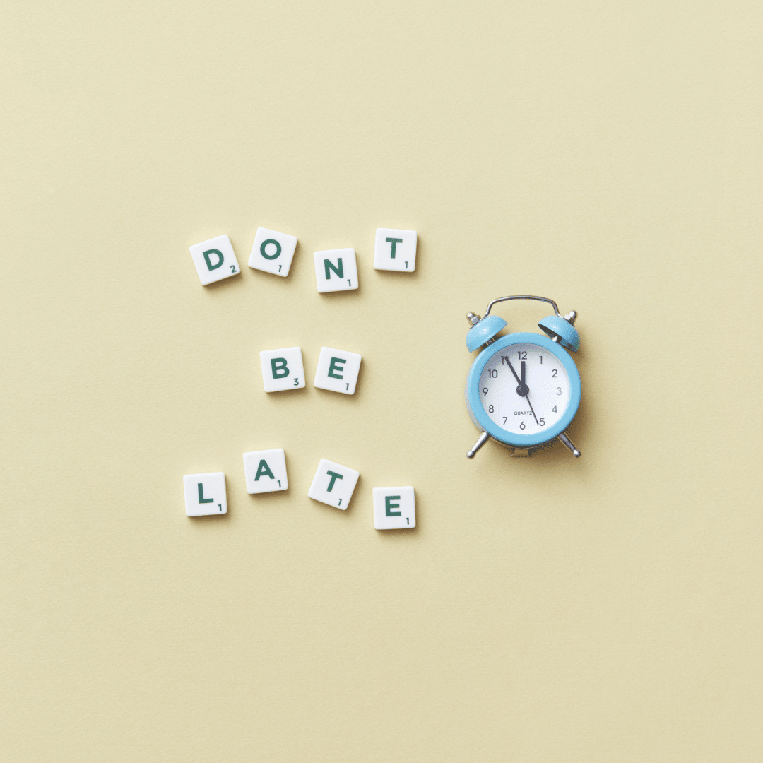 letter tiles spell out the phrase 'don't be late' next to an old-fashioned alarm clock