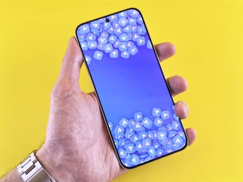 Hand holding a smartphone with a blue screen.