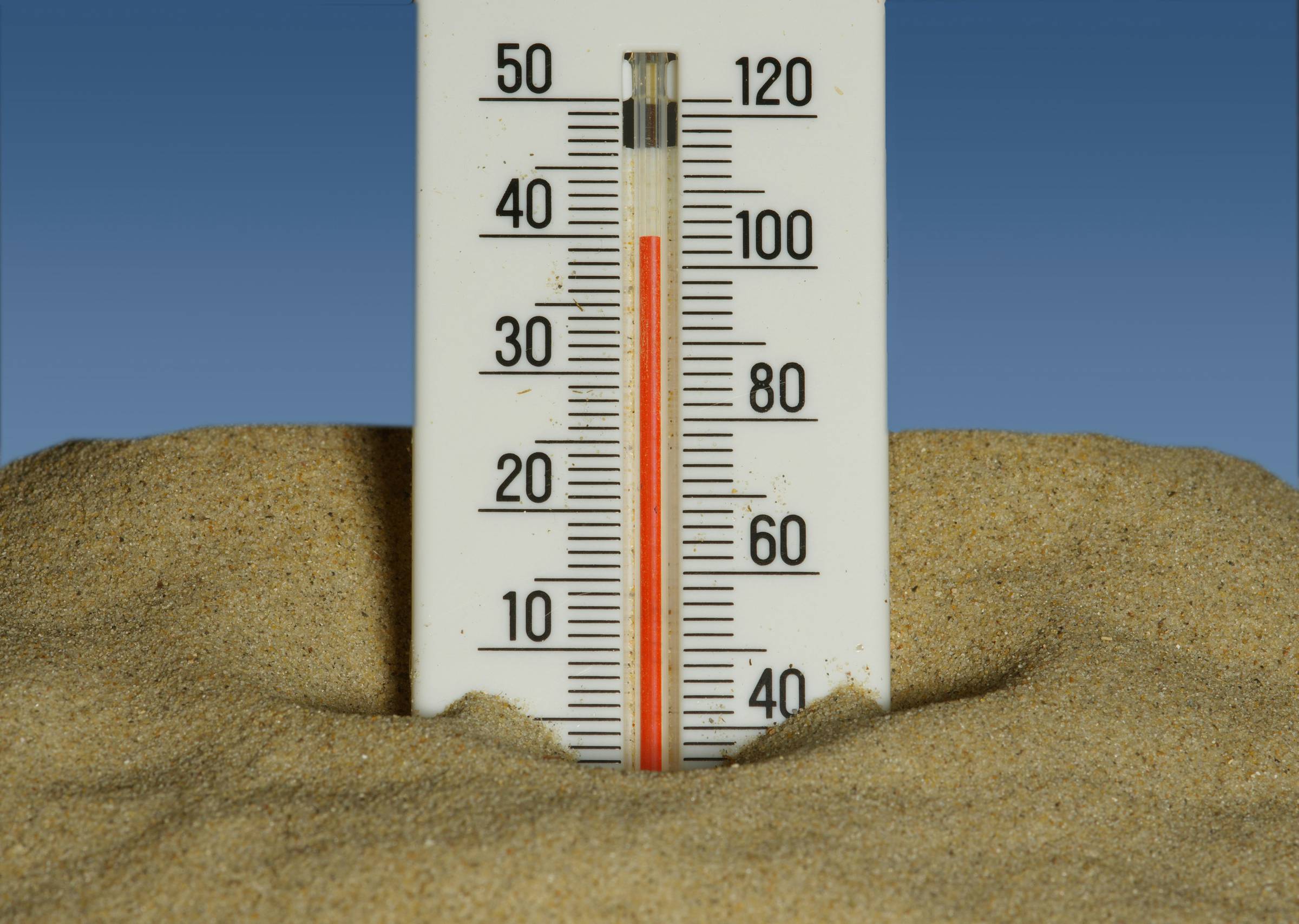 A thermometer with a high temperature in the sand
