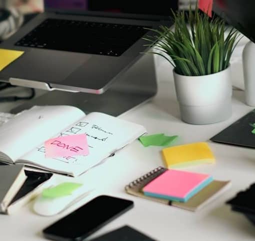A cluttered desk with various office supplies.
