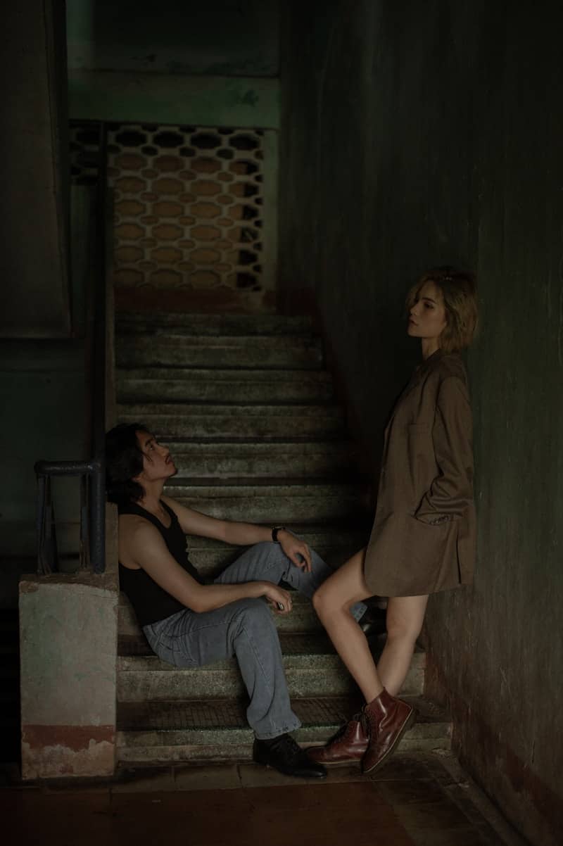 A man and woman on old, dark stairs.