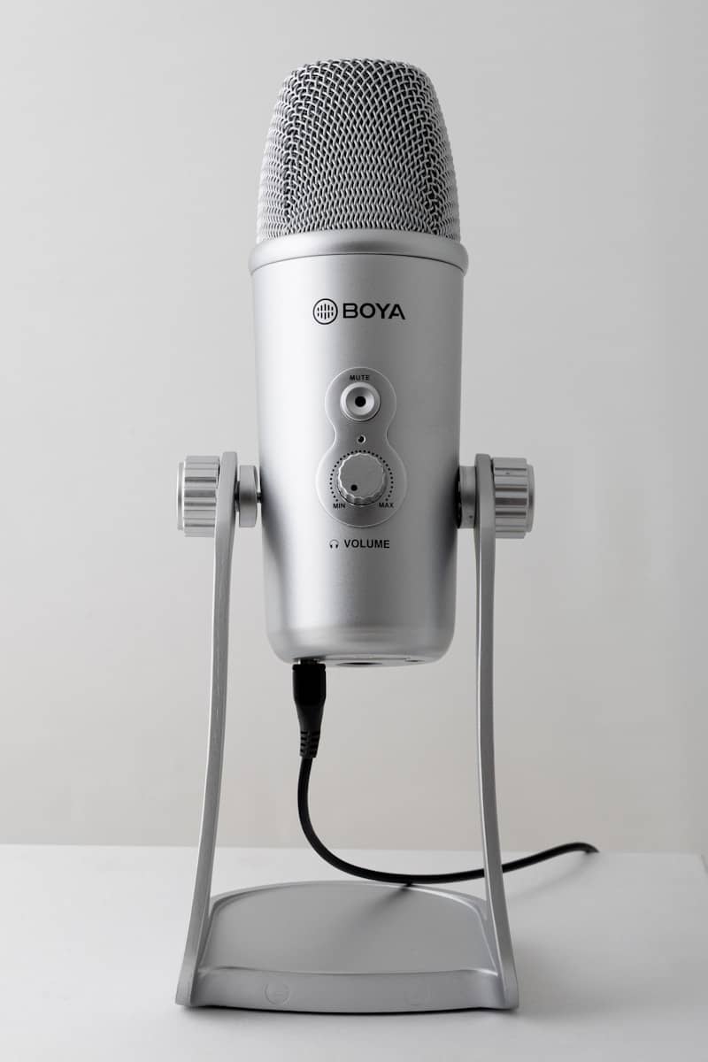 A silver microphone with a stand on a white surface