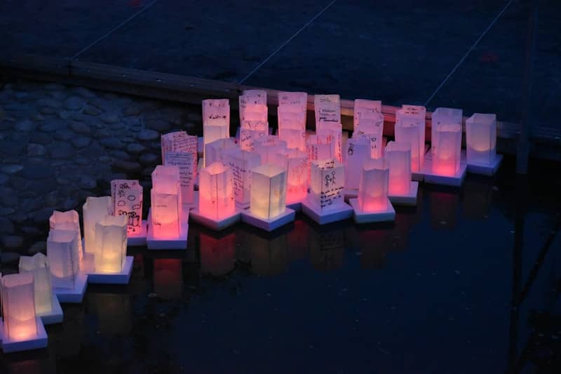 Floating lanterns glow on dark water at night.
