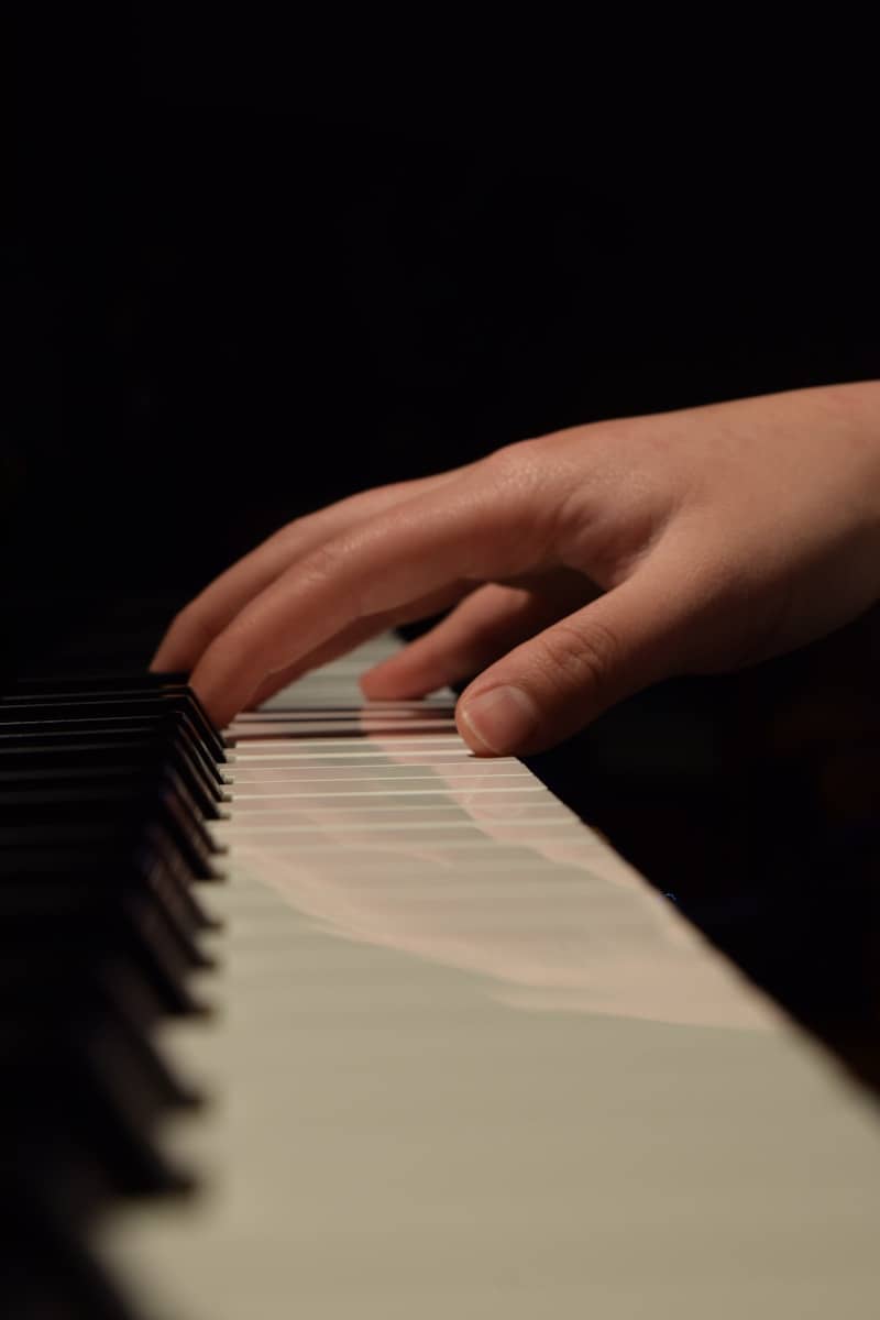 A close-up of a hand playing a piano