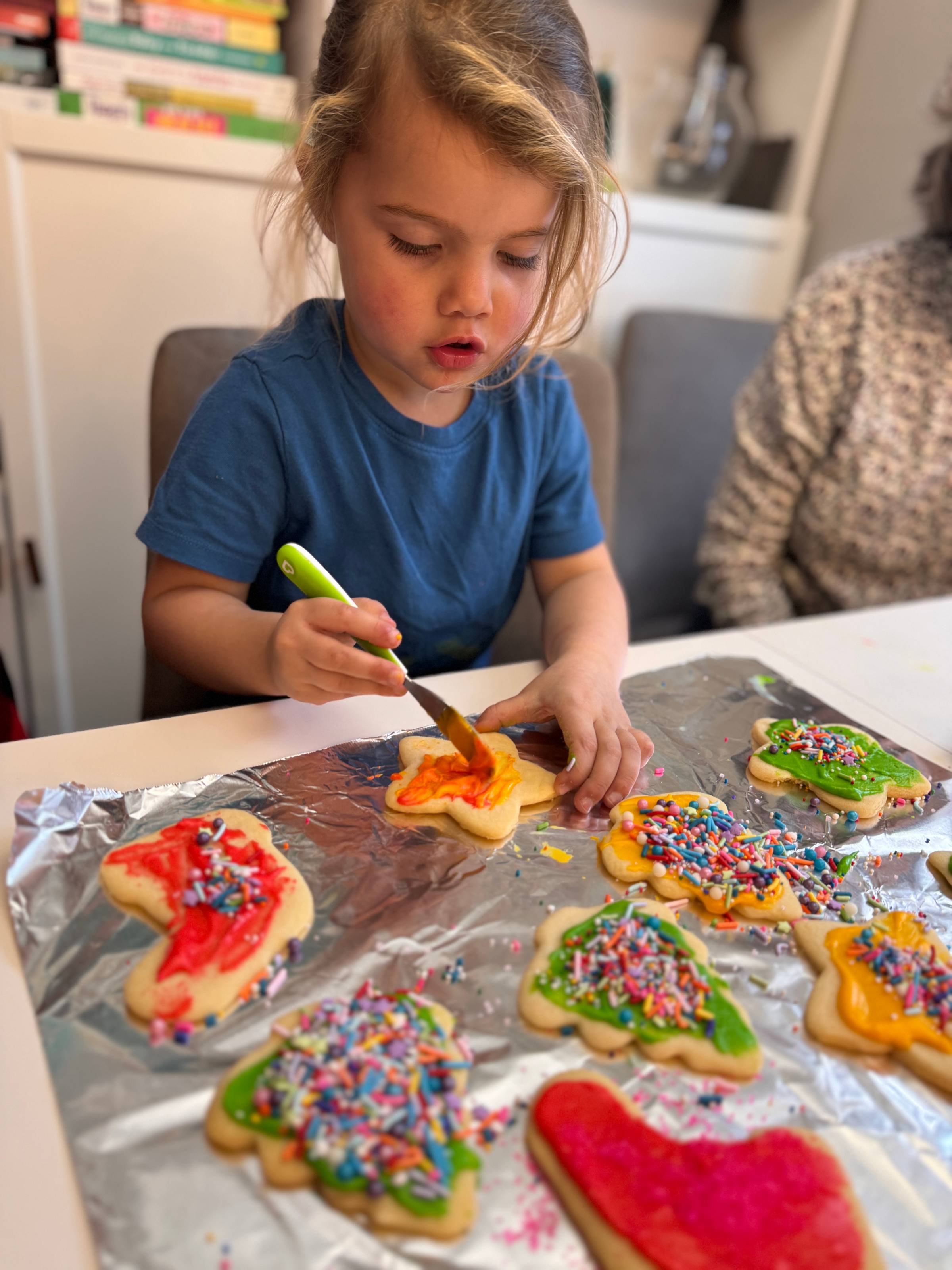 A little girl frosting Christmas cookies