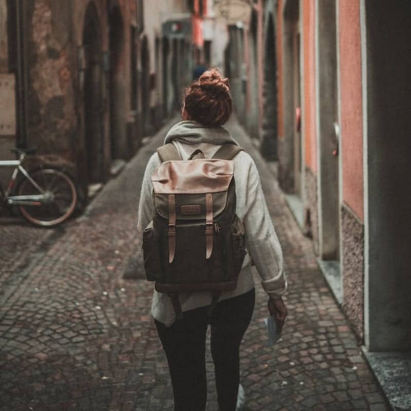 woman walking on street surrounded by buildings