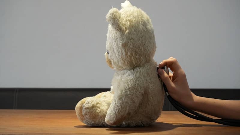 Hand using stethoscope on a teddy bear's back