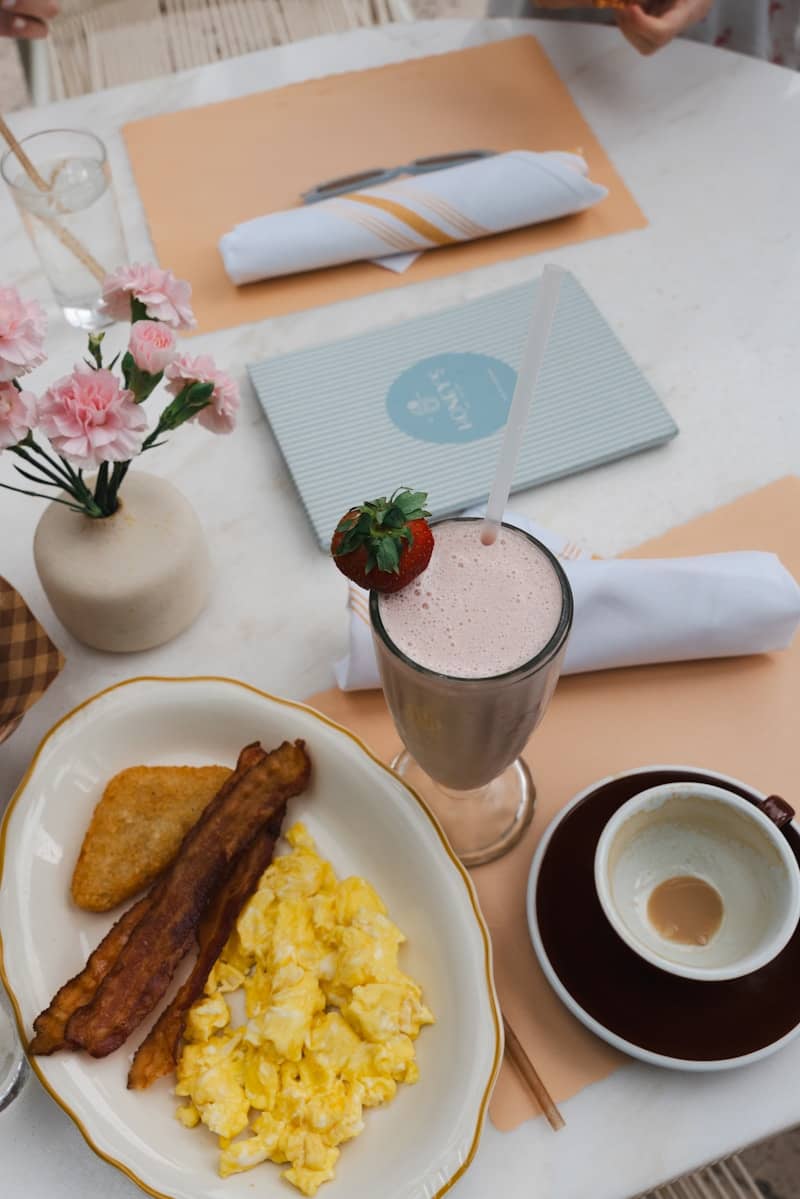 Scrambled eggs, bacon, hash brown, and strawberry milkshake.