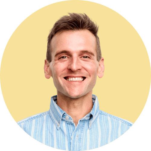 Kaleb Wyse standing in front of yellow background wearing blue shirt.