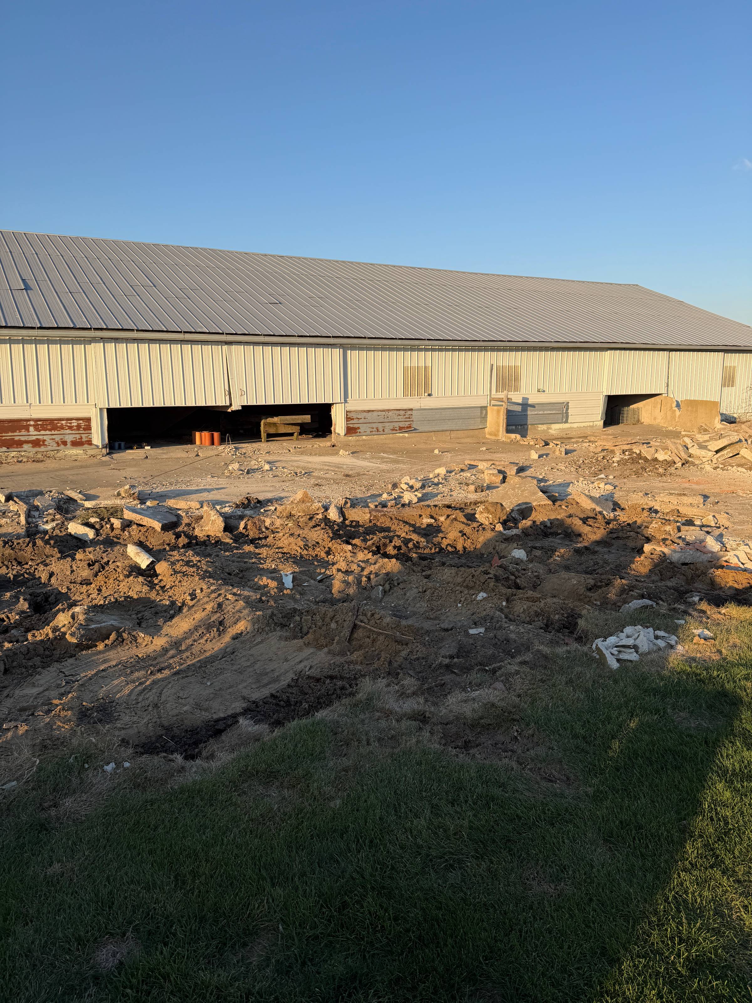 Old farm building with concrete being ripped up.
