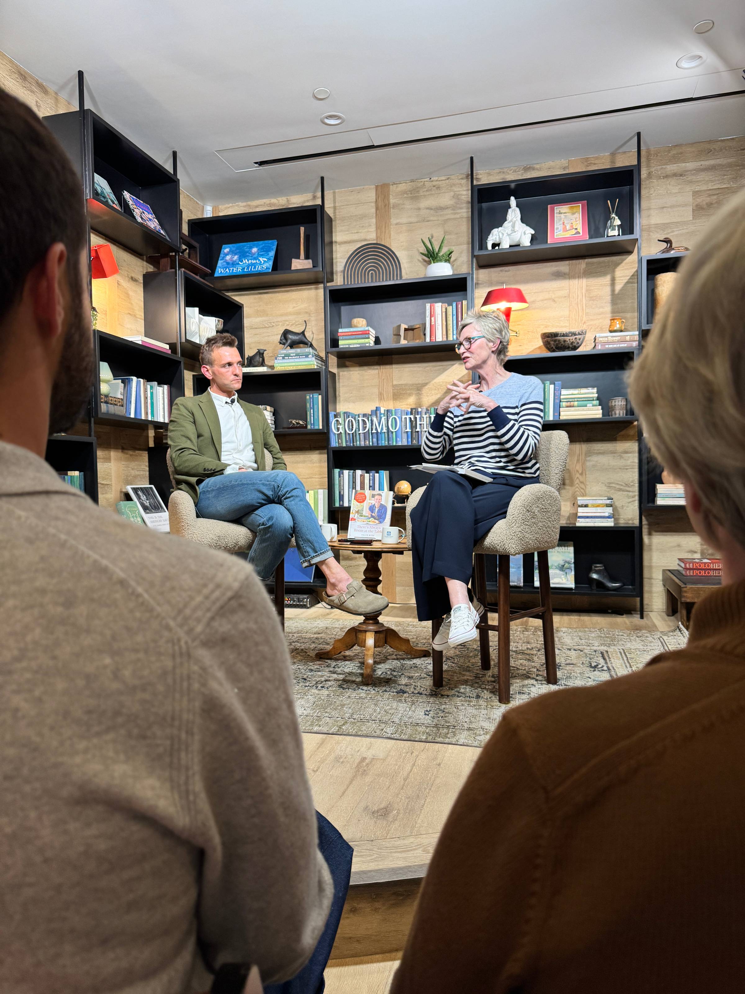Kaleb Wyse and Jane Lynch sitting in chairs chatting.